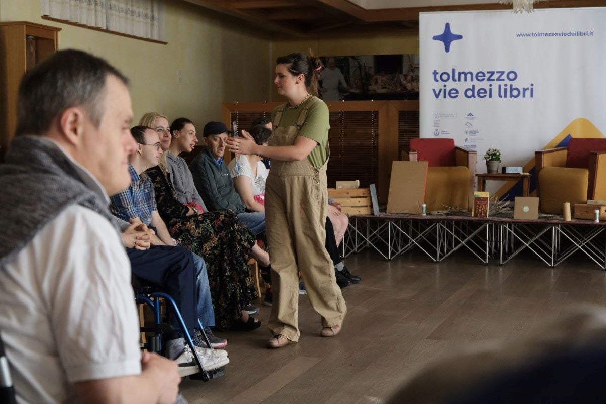 Un membro dello staff mostra uno specchio ad un gruppo di persone con disabilità durante un'attività
